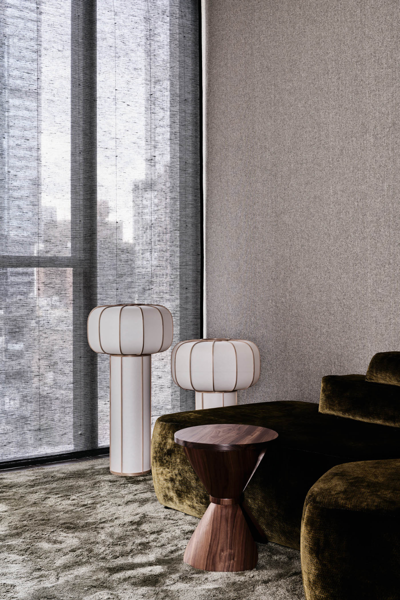 Layered lighting in a moody winter interior featuring sculptural floor lamps, olive velvet sofa, and soft textured carpet.