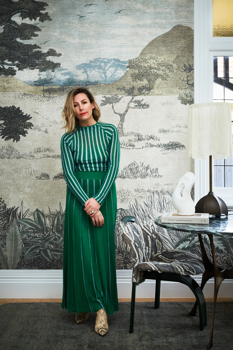 Simone Haag standing in a green dress against a designer wallpaper backdrop
